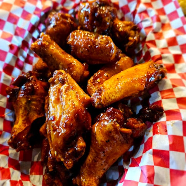 A basket of Blazing Chicken Shack II's glazed chicken wings on red and white checkered paper.